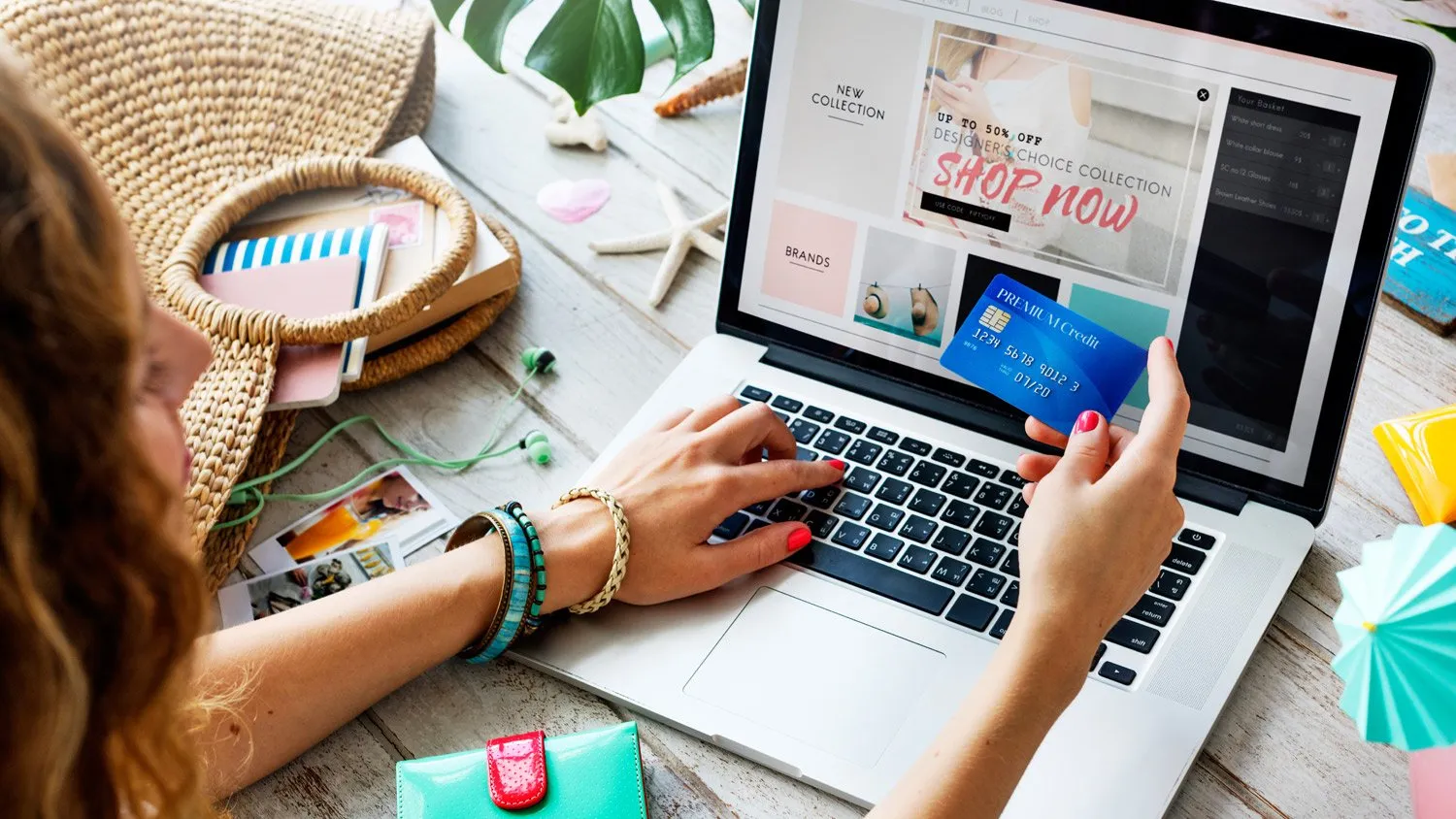 Mulher compra pela internet no notebook, com o cartão de crédito na mão
