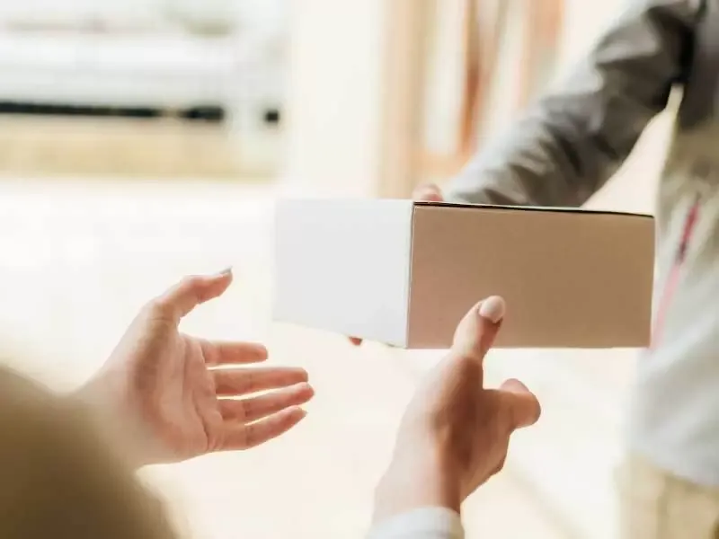 Mãos estendidas para receber uma caixa de encomenda