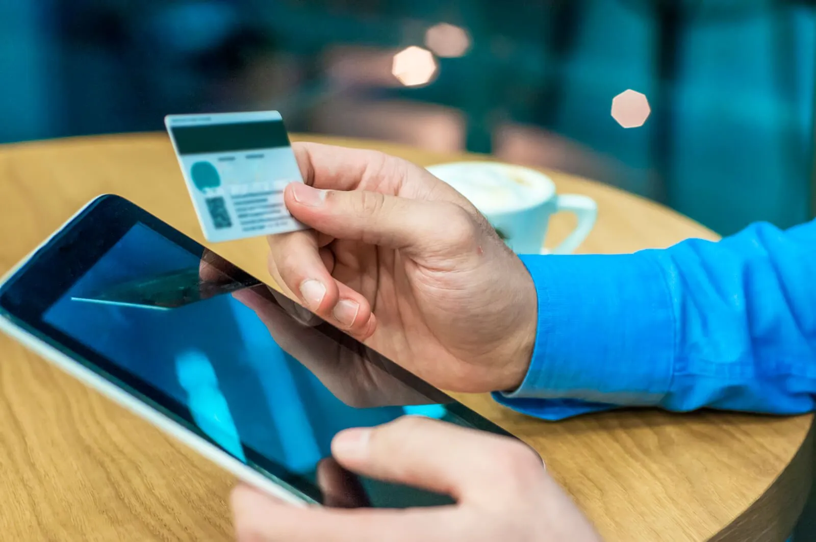 Pessoa segura um cartão de crédito e um tablet para fazer uma compra online